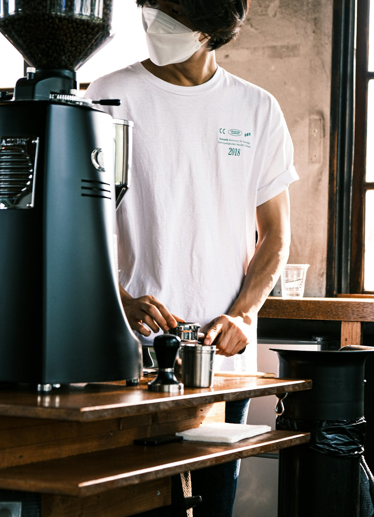 a man wearing a face mask while preparing a drink