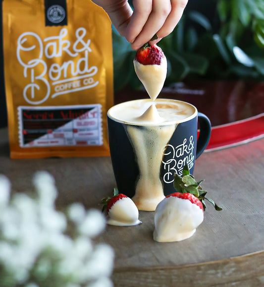 a person dipping a strawberry into a cup of coffee