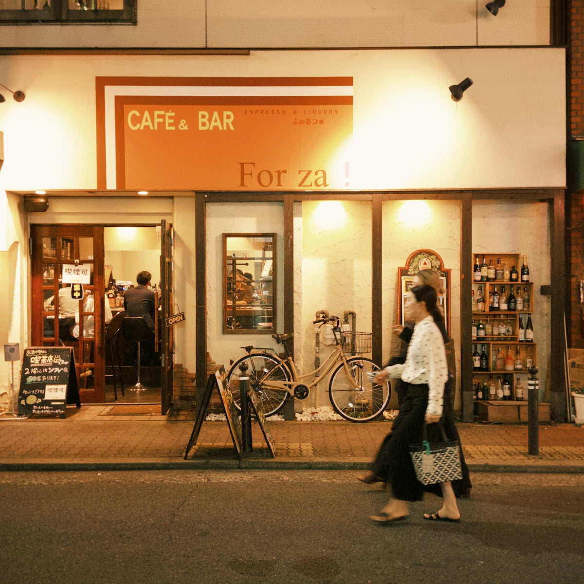 A woman walking down the street in front of a cafe