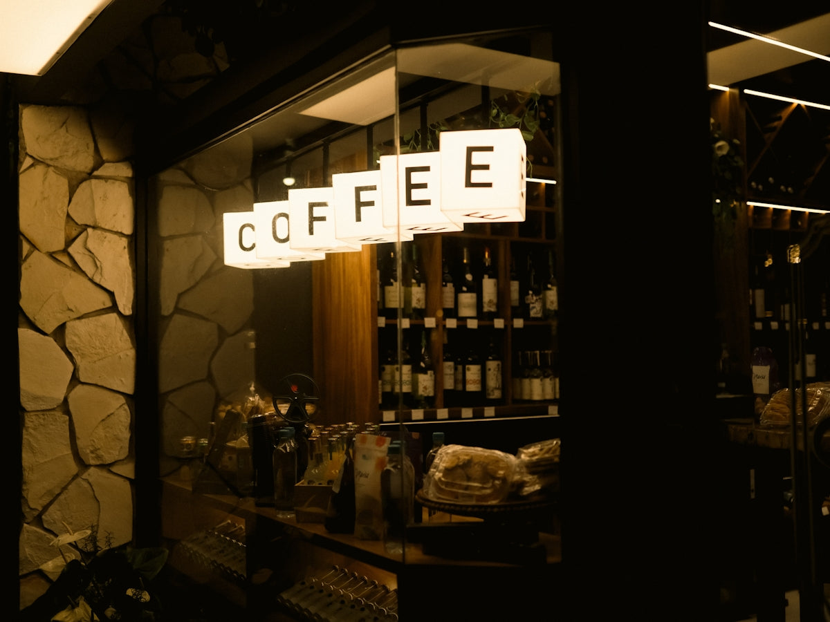 Coffee sign illuminated above bar with bottles.