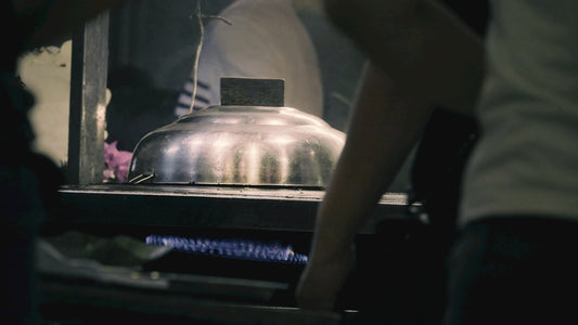 People gathered around a steaming food cart at night.